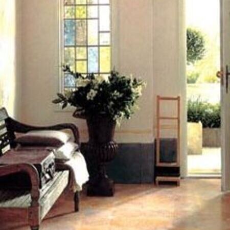 Elegante Zimmerecke mit Chaiselongue, großer Pflanze, Buntglasfenster und Terrakottaboden.