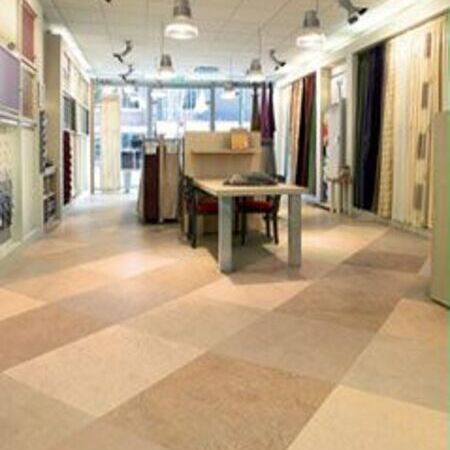 Innenraum eines Stoffladens mit Auslagen an den Wänden und einem Tisch in der Mitte.